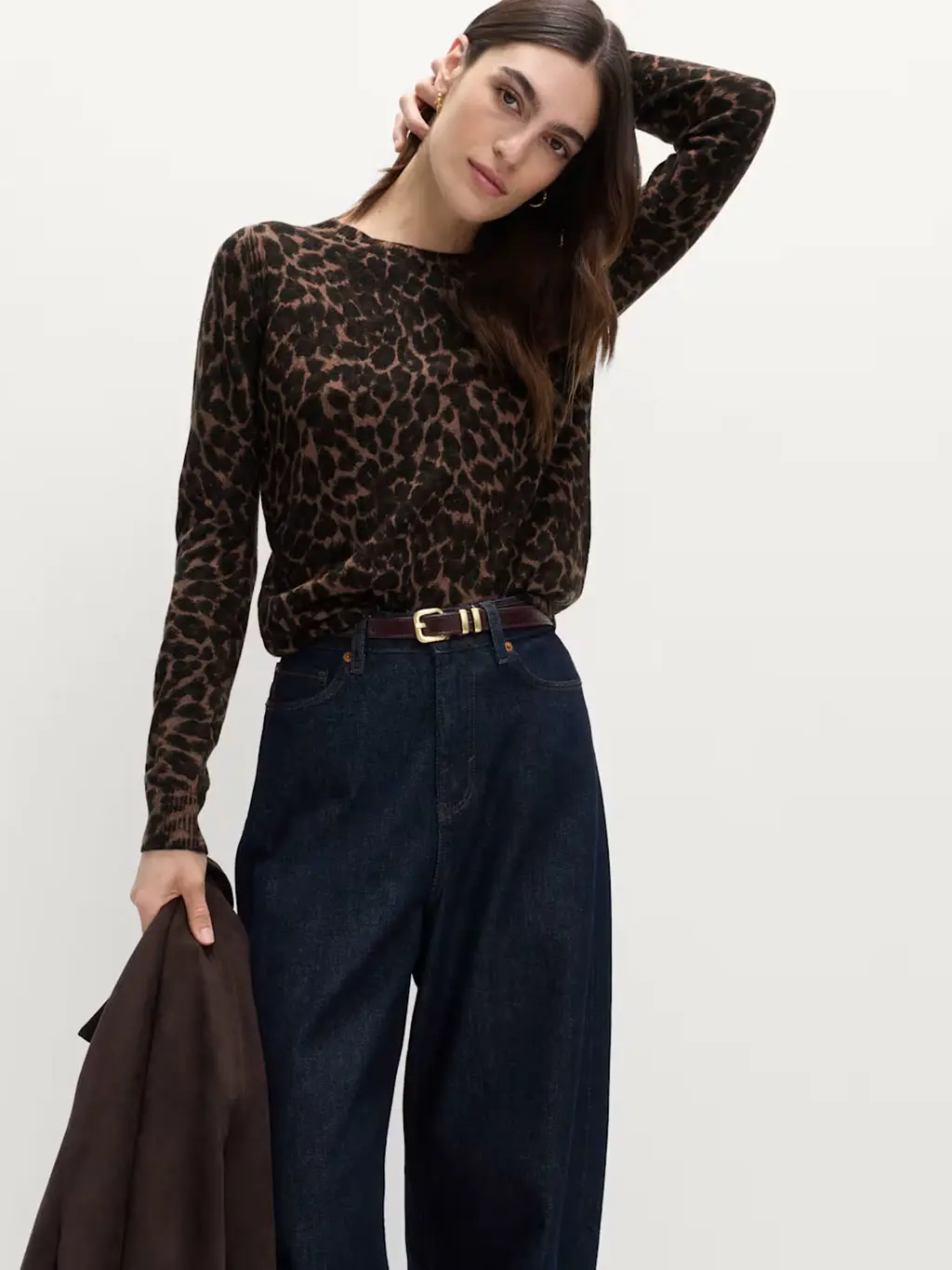 Woman wearing a leopard-print jumper with indigo blue jeans and a brown belt