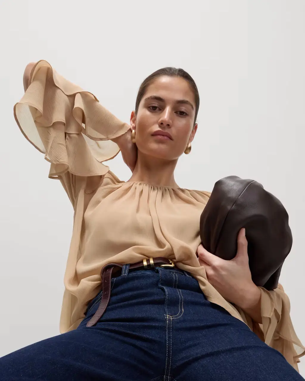 Woman wearing dark cream frilled blouse. 