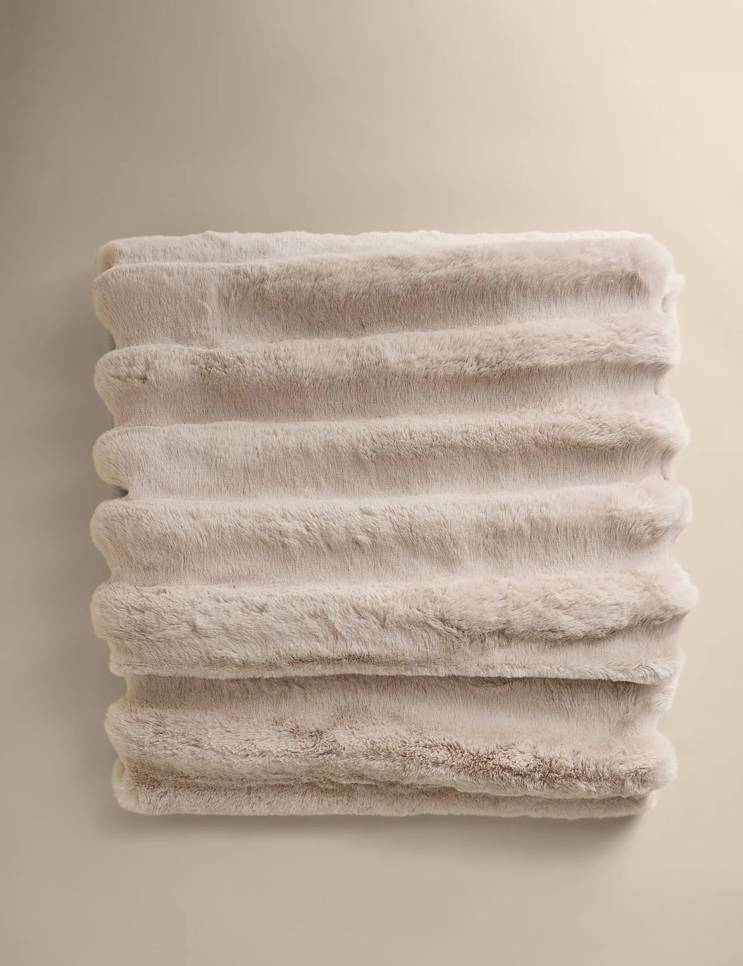 Soft fluffy faux fur blanket in a beige colour.