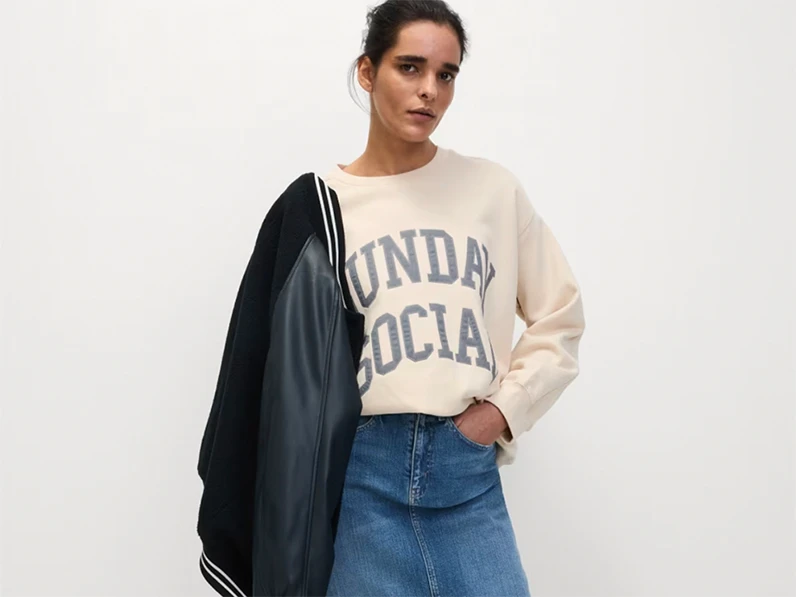woman wearing cream sweatshirt and denim skirt