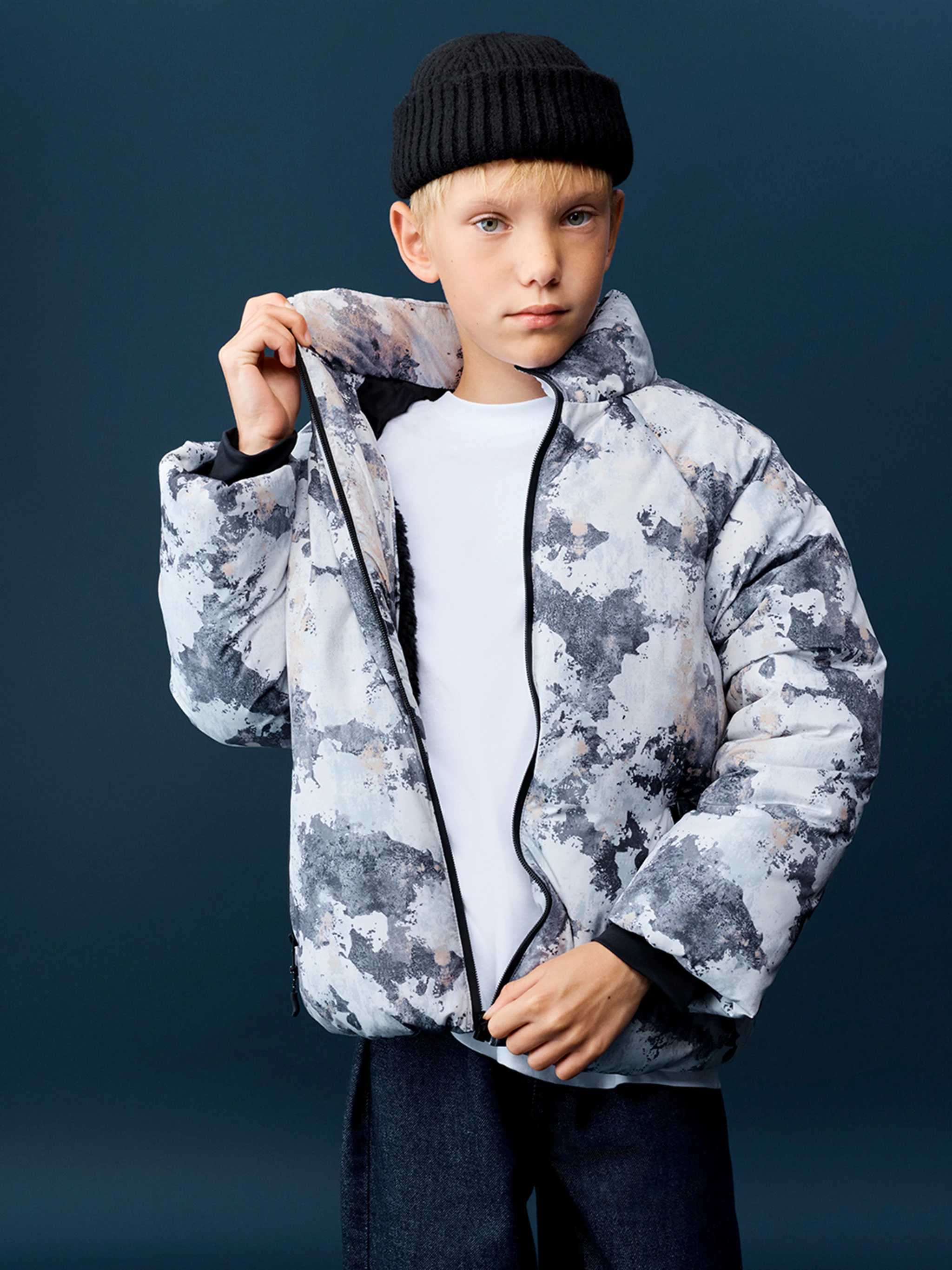 Young child in a white and grey camouflage-print puffer coat.
