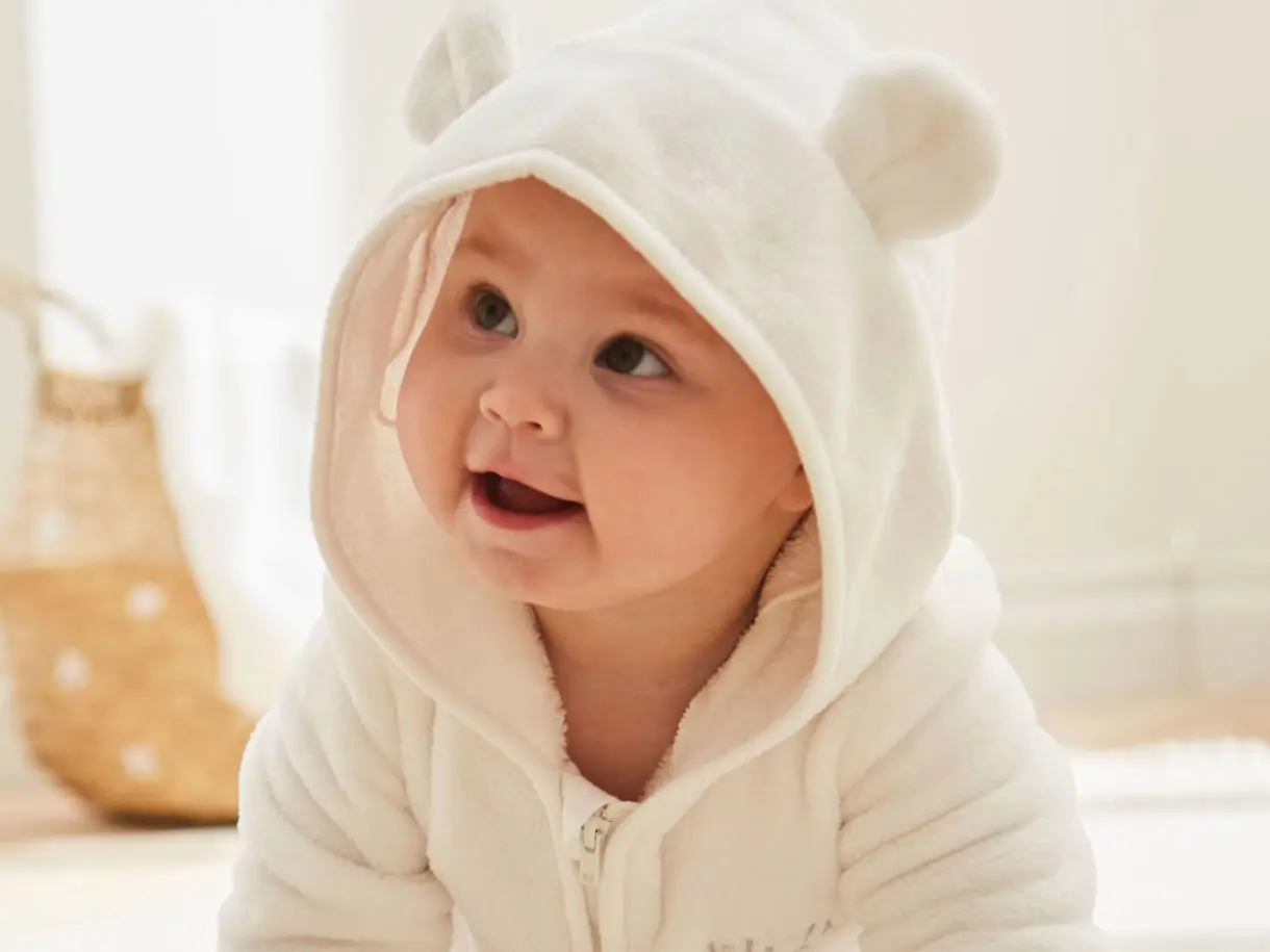 Baby wearing hooded white fleece onesie with ears