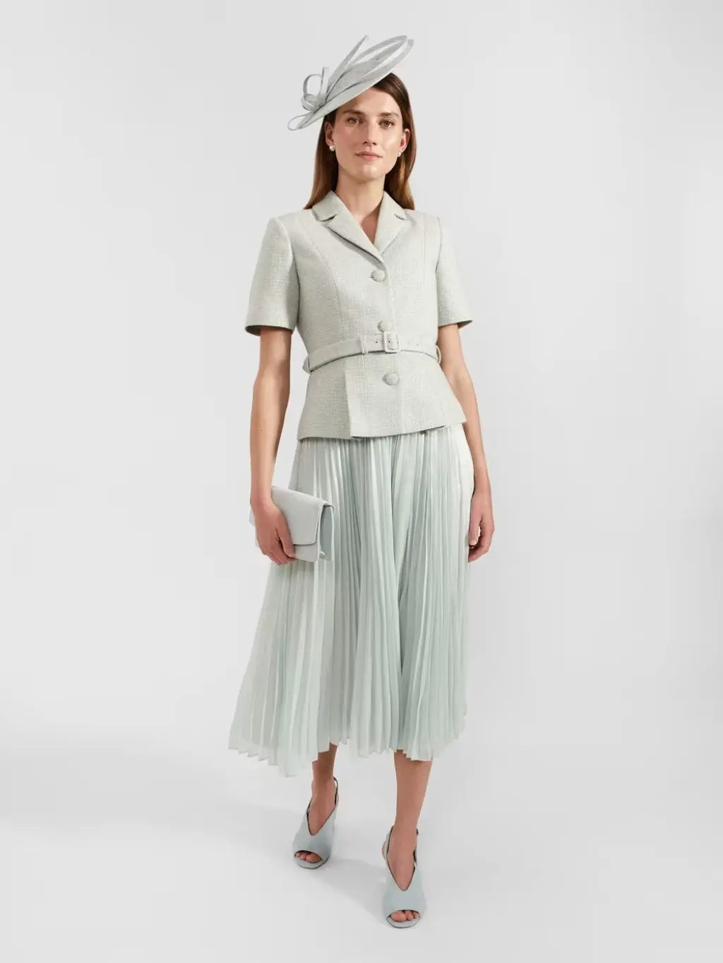 Woman wearing a pale green dress, short sleeve tailored jacket and fascinator at M&S