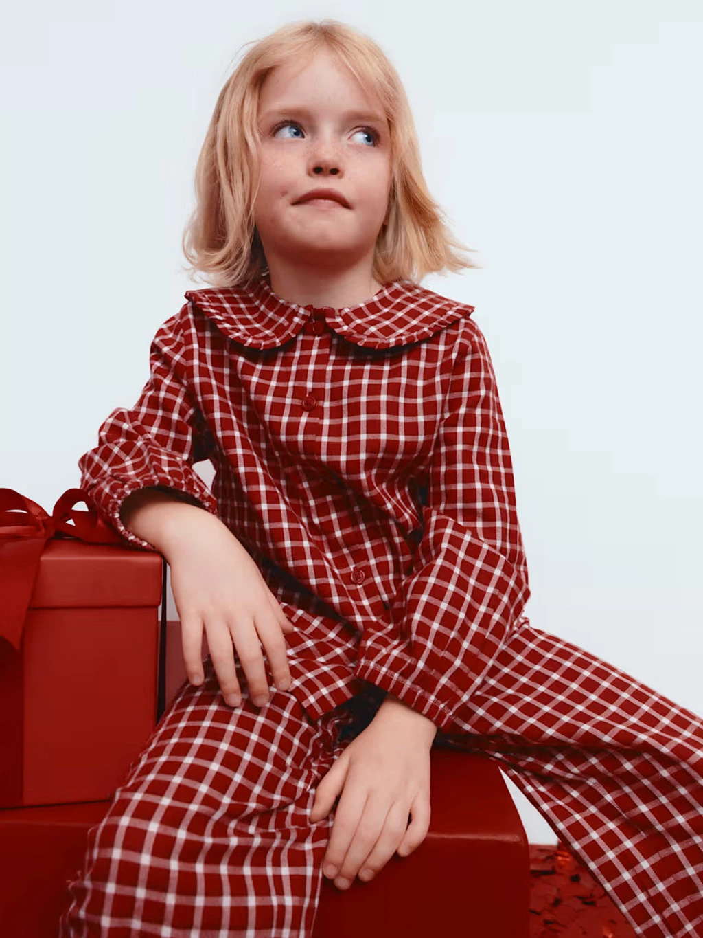 Young girl in a pair of red checked pyjamas.
