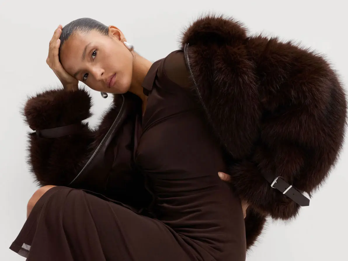 Woman wearing long brown dress and a brown faux-fur coat