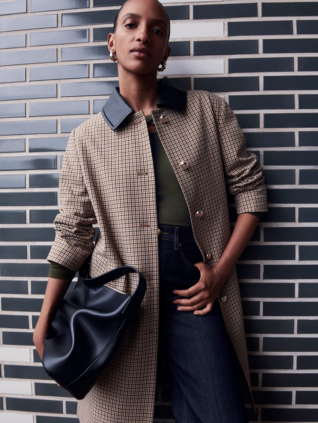 Woman wearing a light brown checked coat with a contrasting faux leather collar