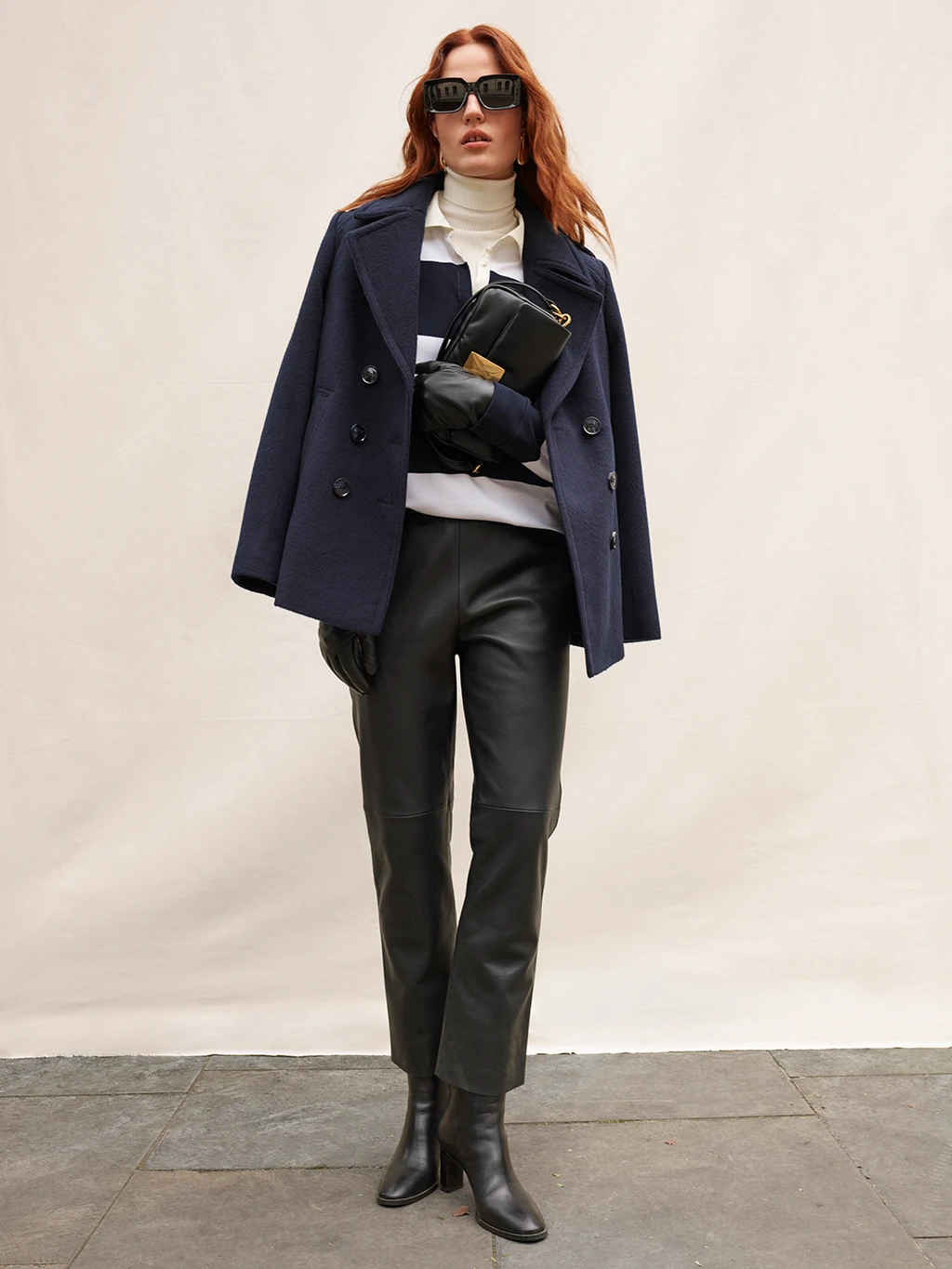 Woman wearing navy tailored wool coat and leather trousers