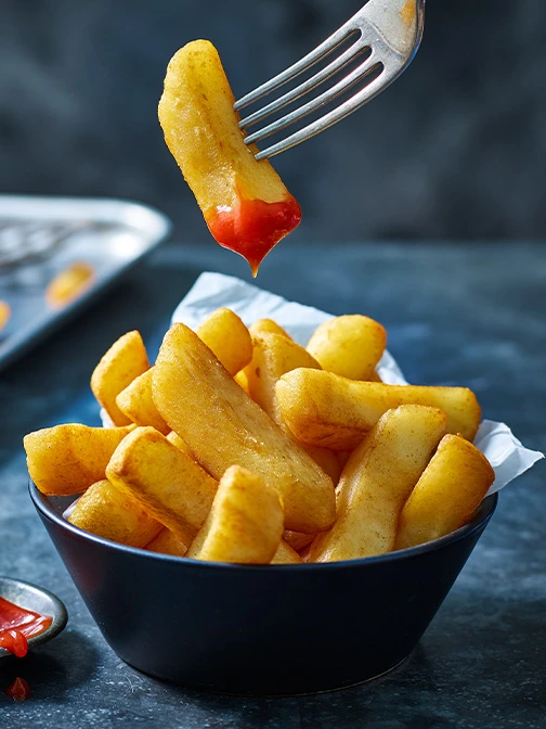 Chunky chips in blue bowl with fork and ketchup