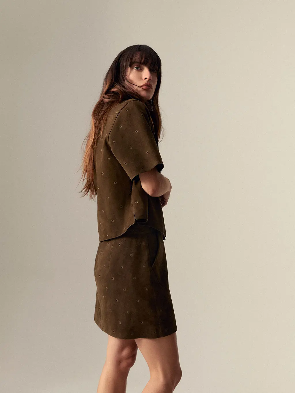 Woman wearing a studded suede jacket and coordinating mini skirt