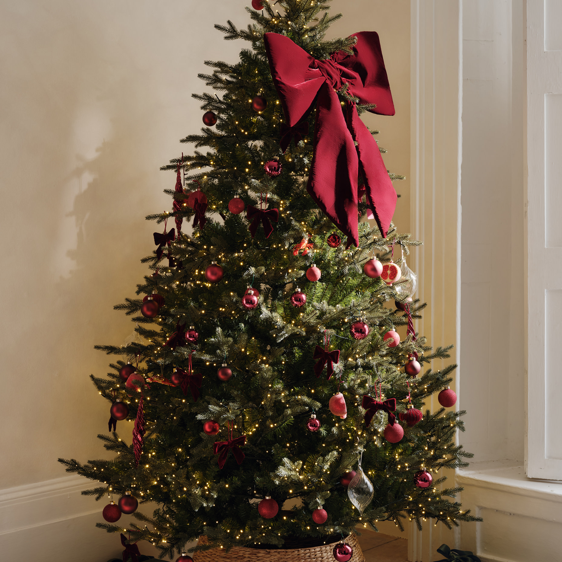 Christmas tree decorated with red baubles and a large red ribbon