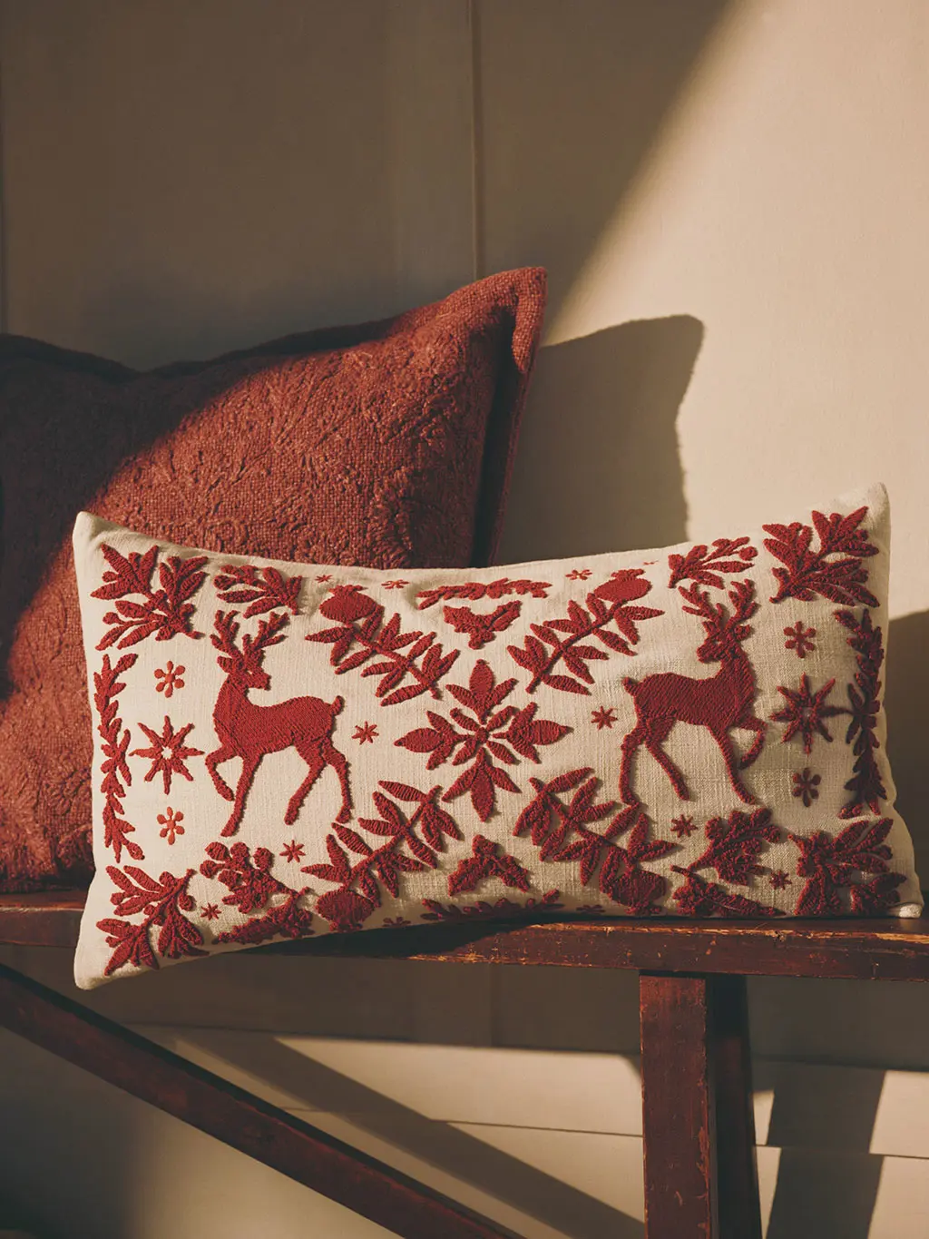 White rectangular cushion with a Christmas embroidered red pattern