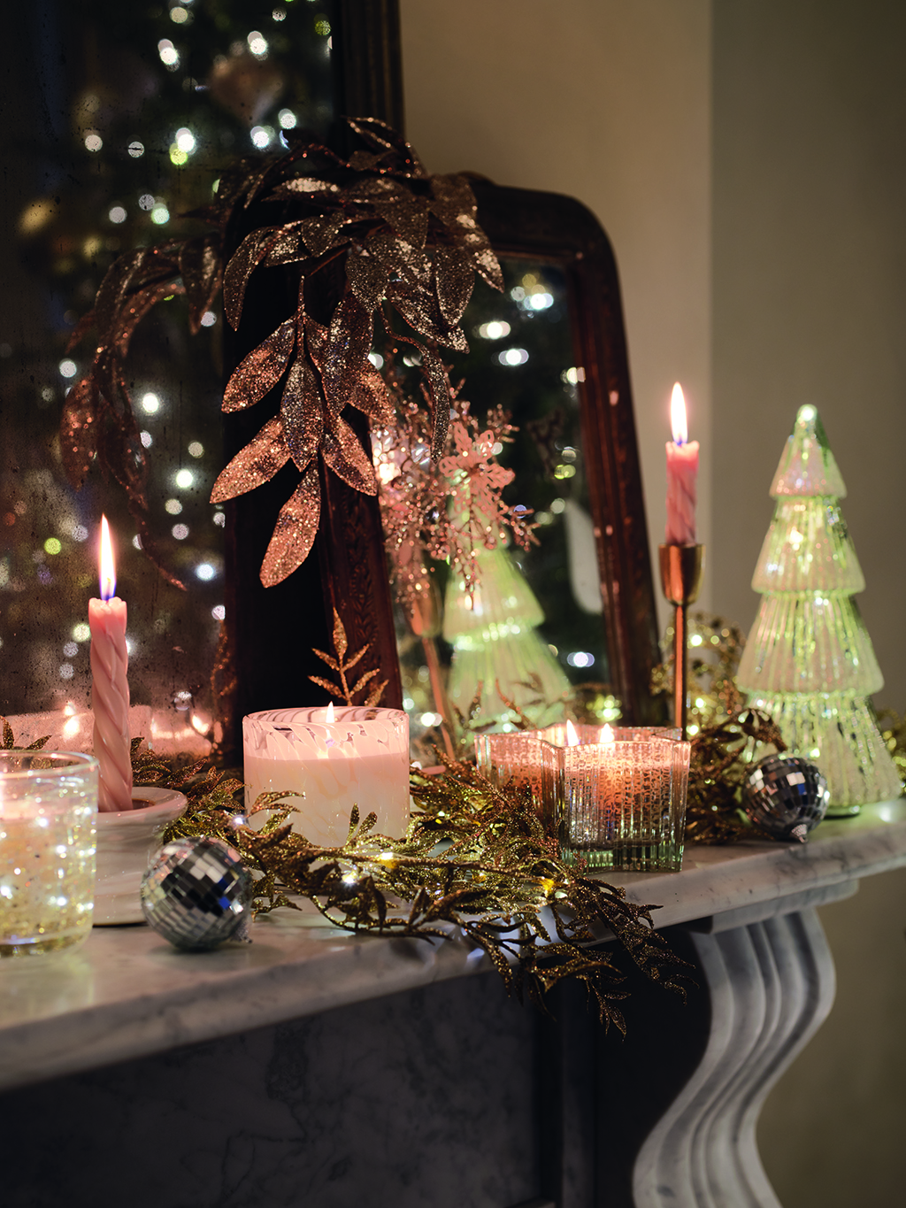 Assorted sparkling Christmas decorations and candles on a mantelpiece