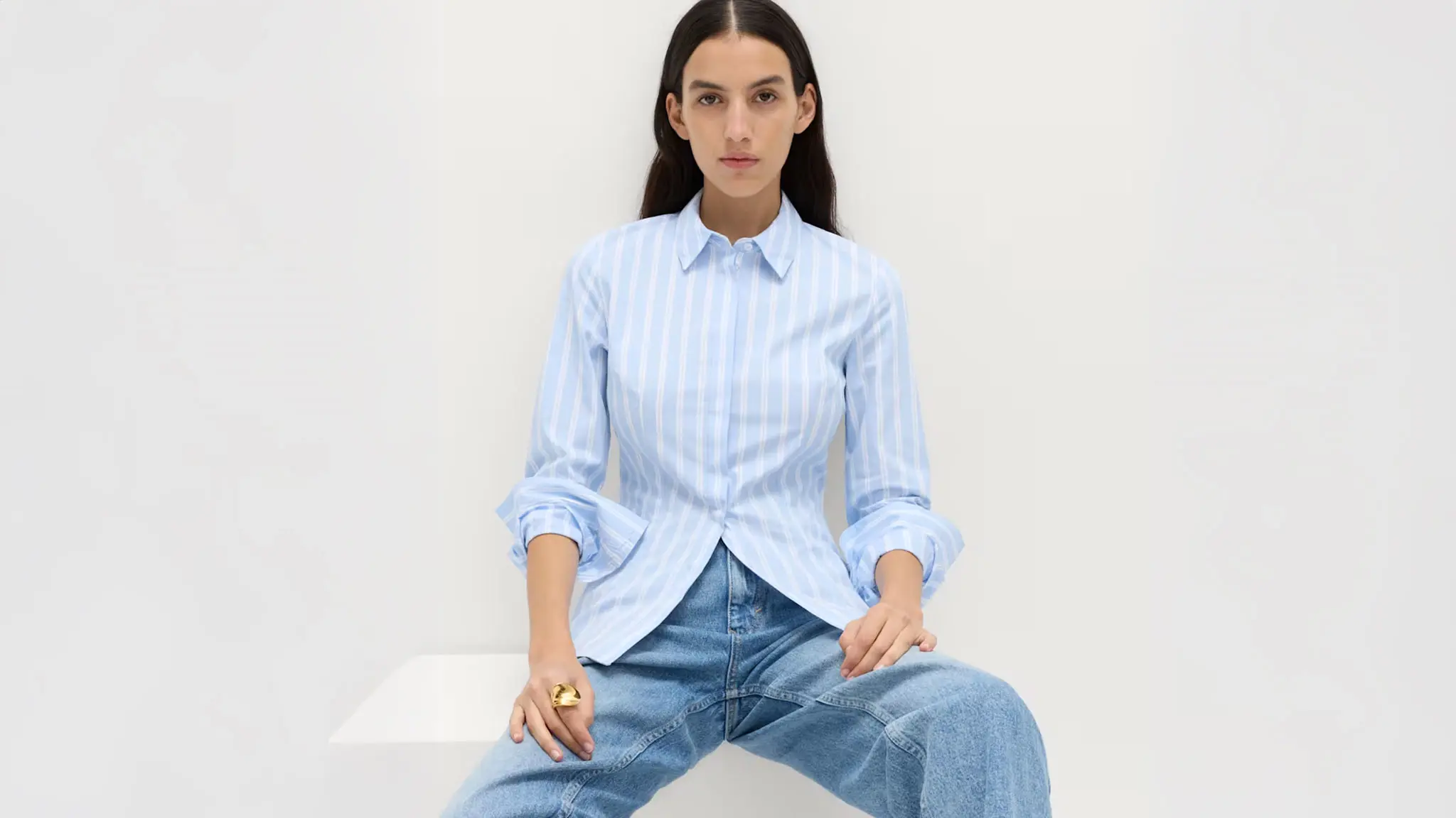 Woman wearing a blue and white striped shirt with blue jeans