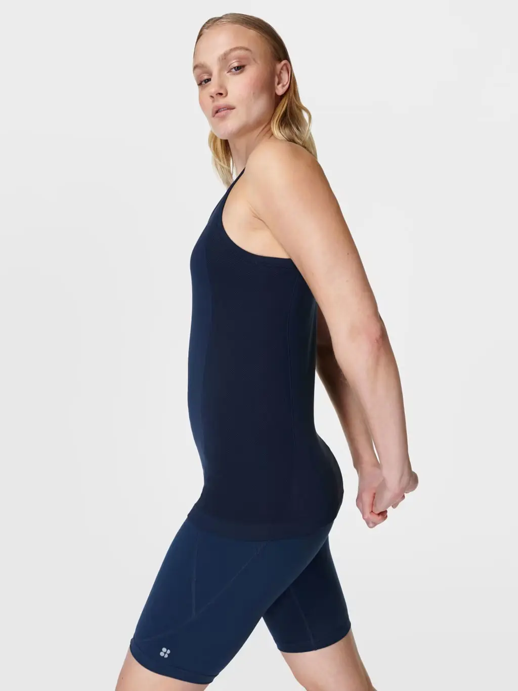 Woman wearing a navy sports vest and bike shorts.