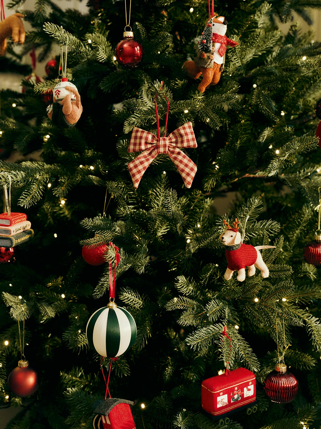 Group of Christmas decorations including a gingham bow, striped baubles and felt animals.
