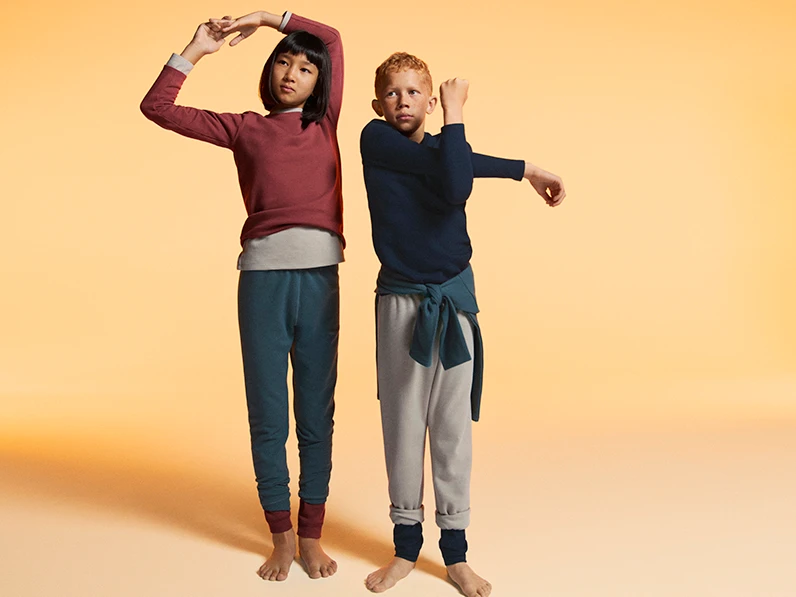Two children wearing assorted winter thermals and joggers