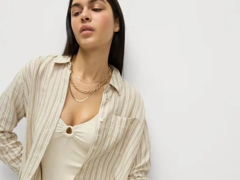 A woman wears a linen shirt over a swimsuit