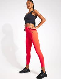 Woman wearing black sports bra and red sports leggings. Shop up to 50% off selected adidas & Sweaty Betty