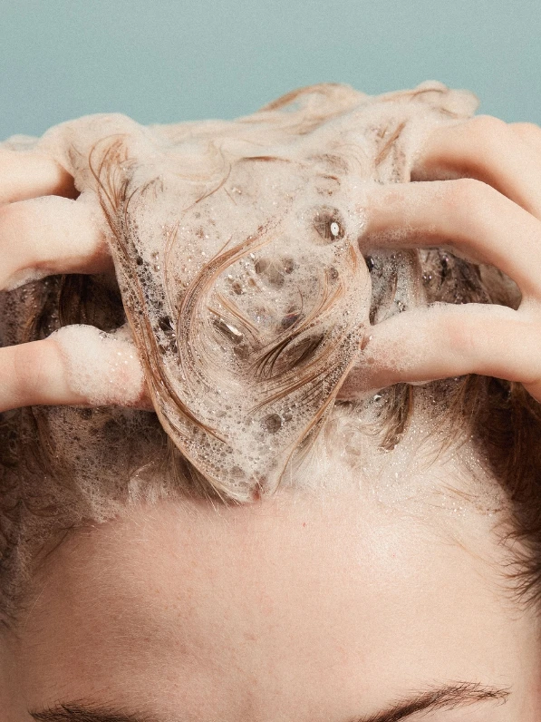 Woman washing hair with shampoo