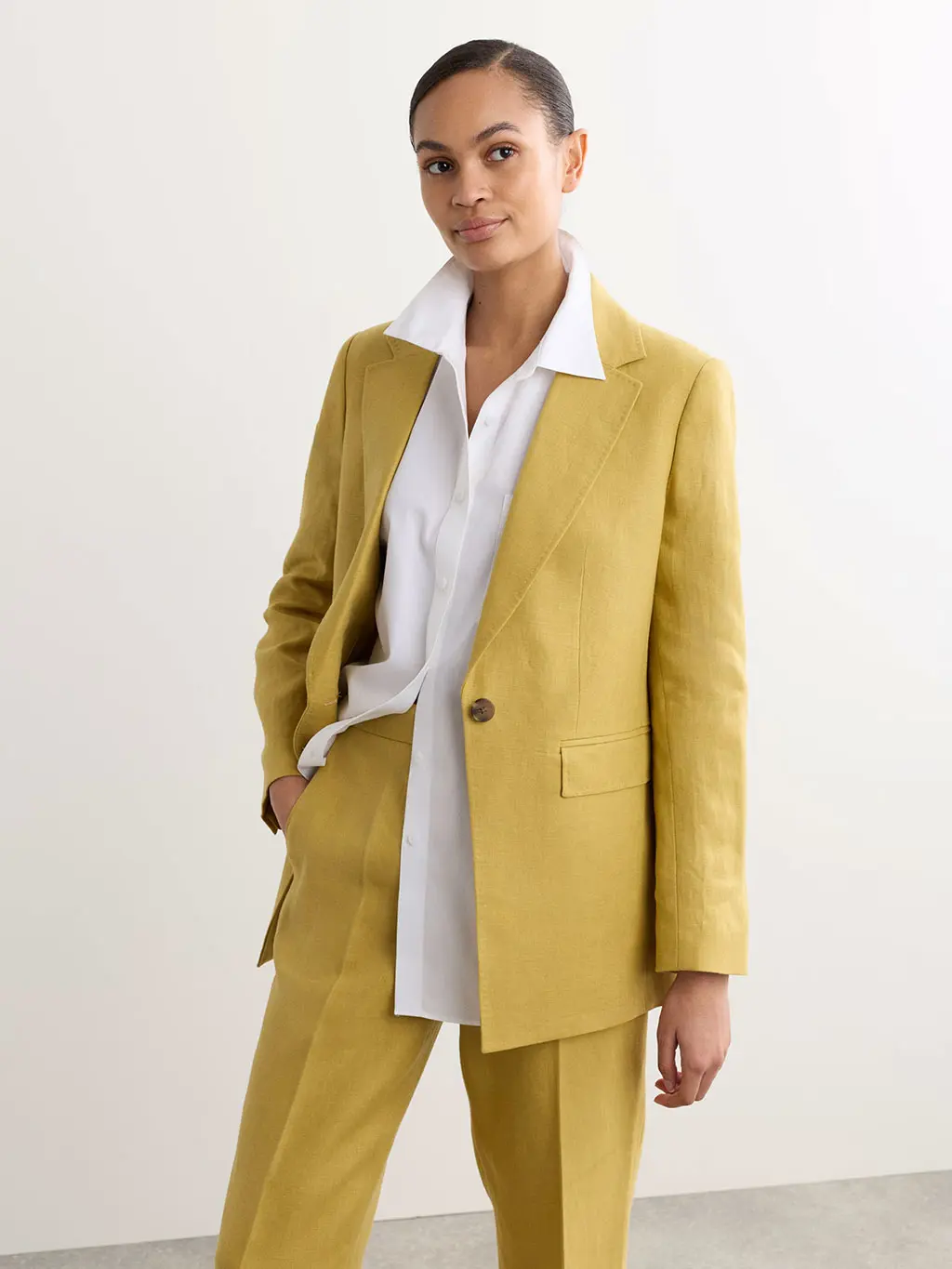 Woman wearing a yellow blazer with matching trousers and a white linen shirt