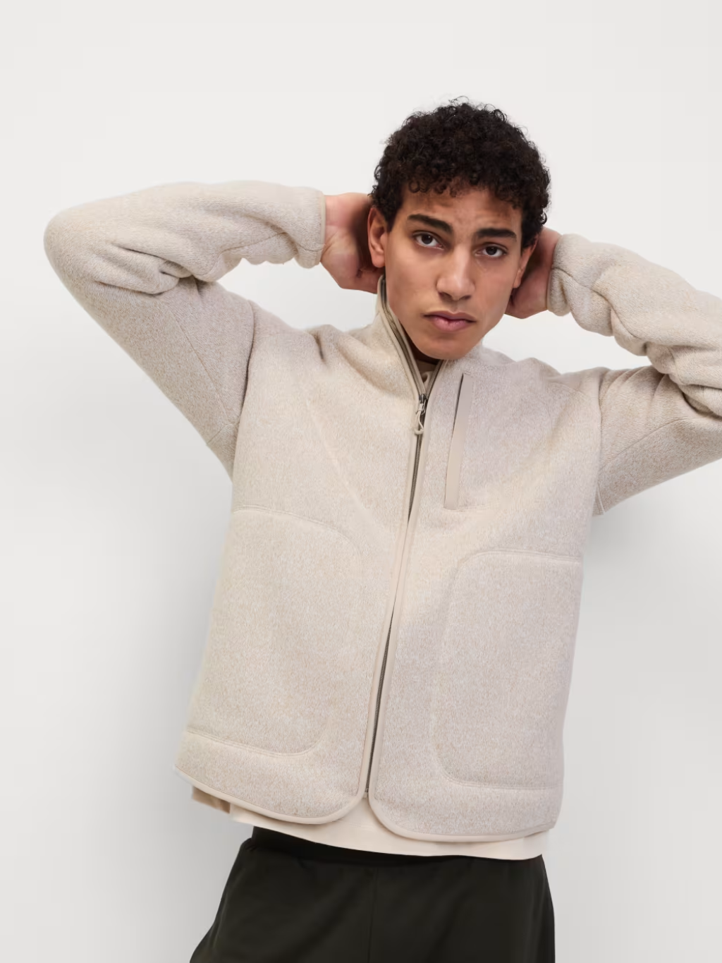 A man wearing a cream fleece jacket with black jogging bottoms