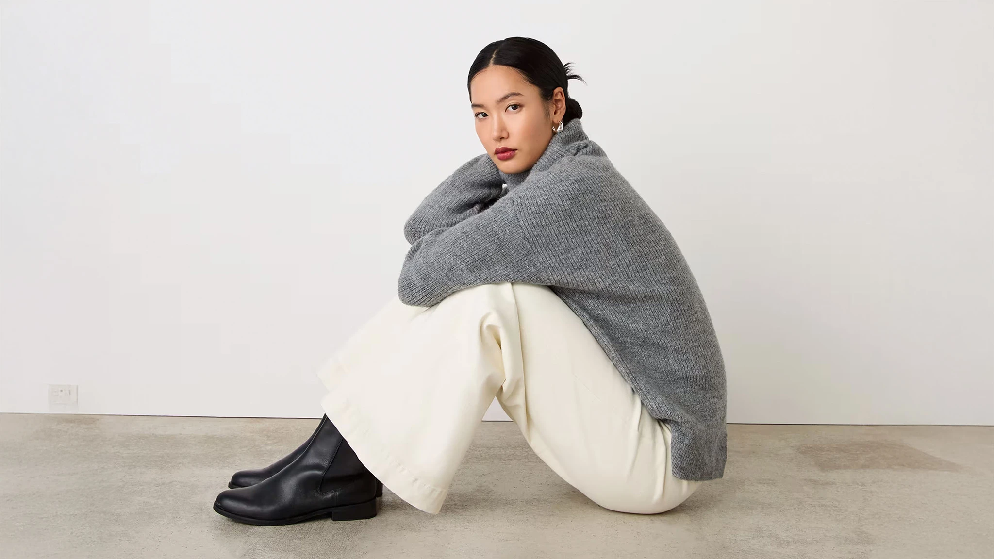 Woman wearing grey jumper, cream trousers and Chelsea boots