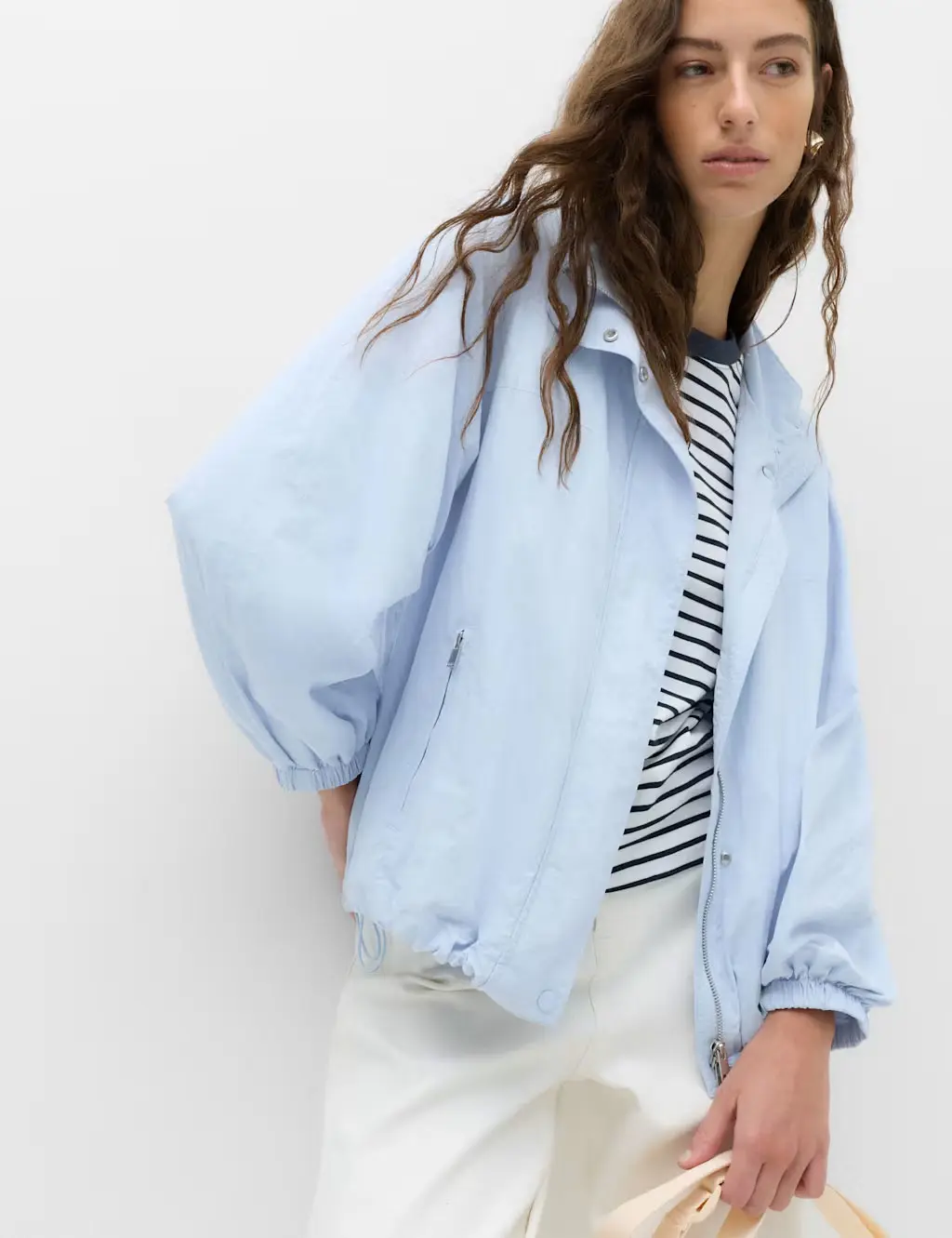 Woman wearing a blue bomber jacket with a striped T-shirt and white jeans