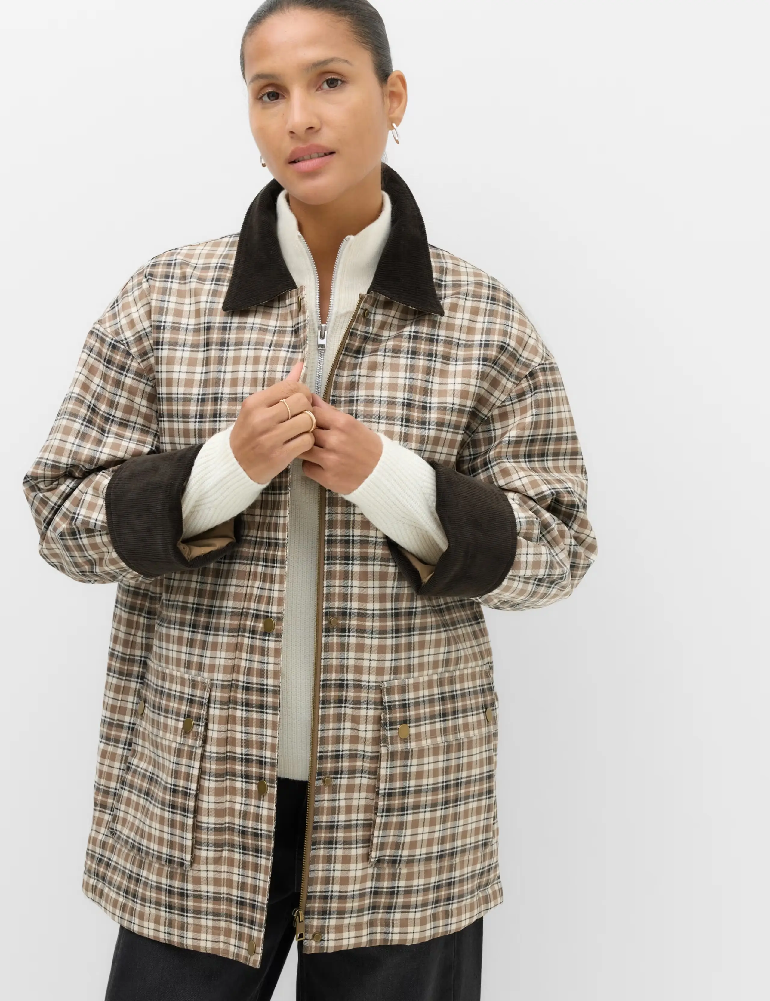 Model in a neutral checked barn jacket with a brown collar and lining.