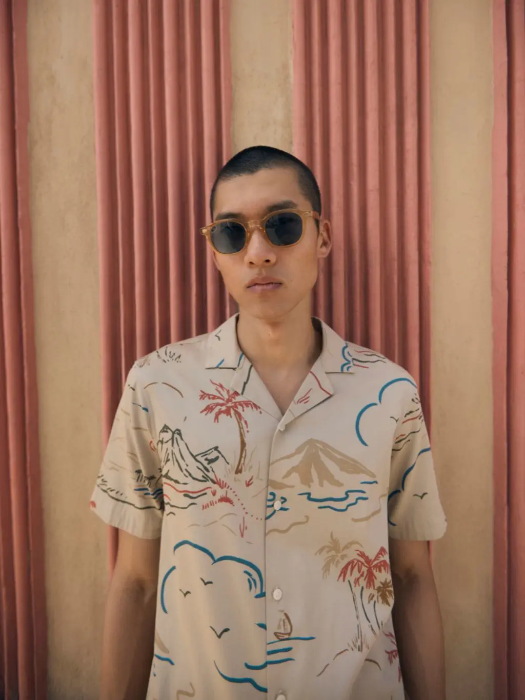 A man wears sunglasses and a Hawaiian shirt