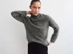 Woman wearing grey funnel-neck jumper with black trousers