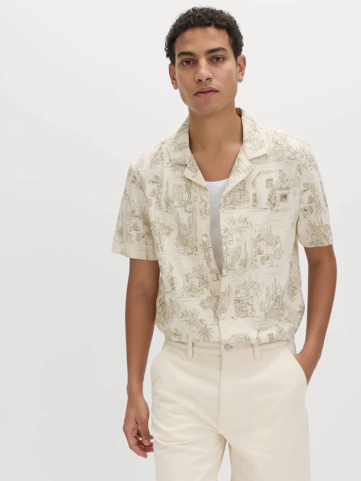 Man wearing printed shirt over white vest and neutral jeans 