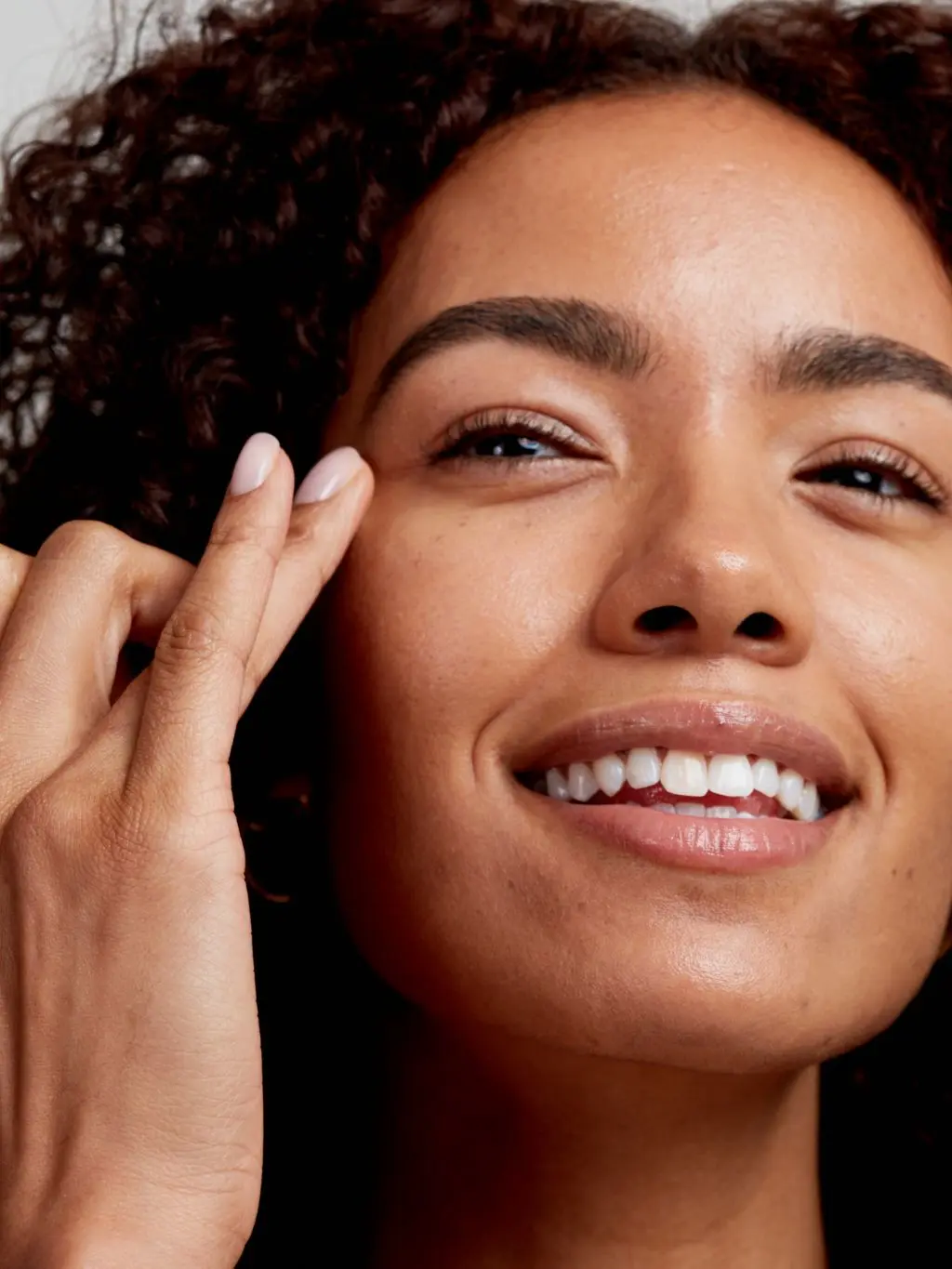 A woman applies eye cream to the fine lines by her eyes
