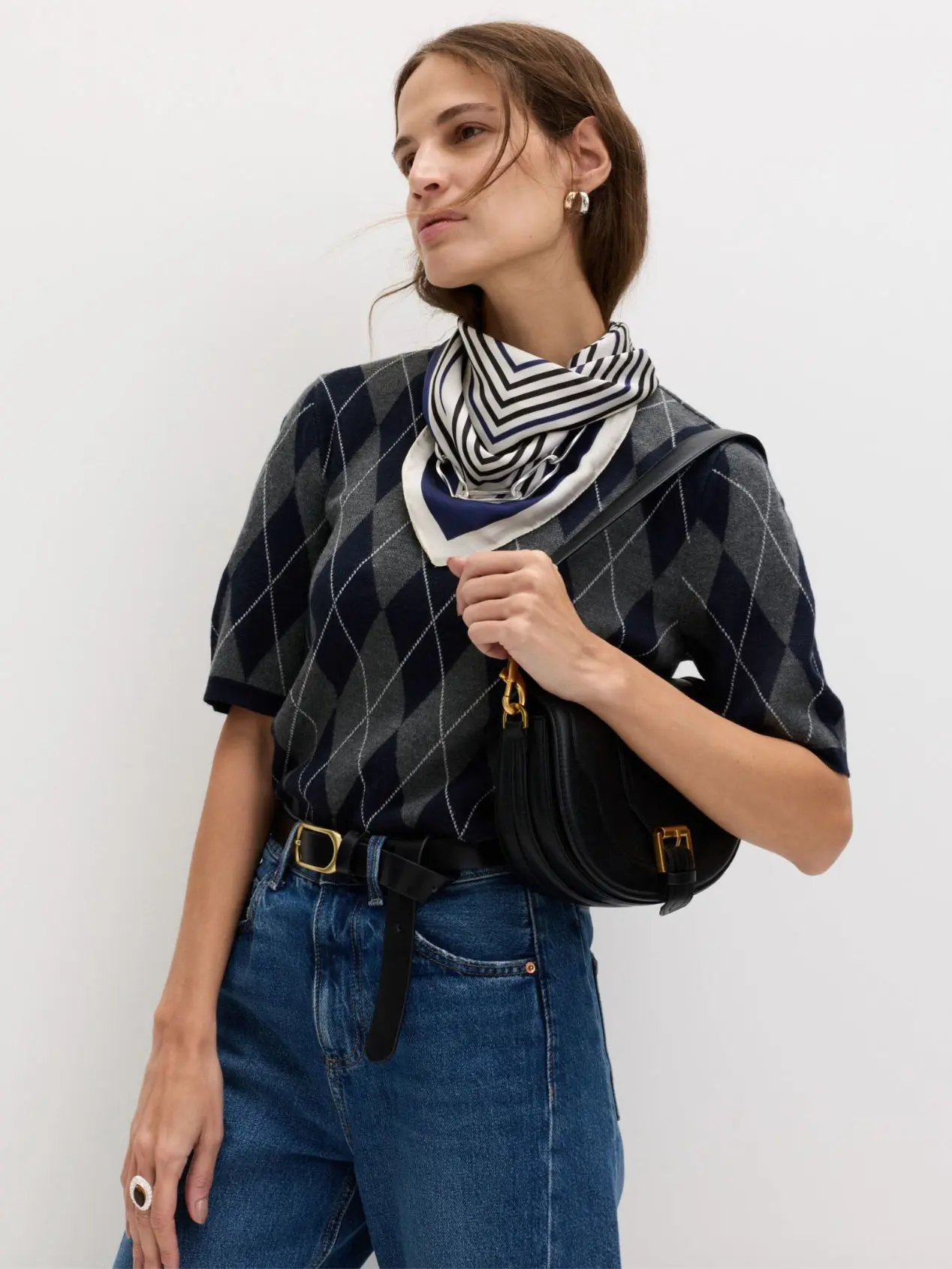 Woman wearing argyle jumper, blue jeans and striped neck scarf
