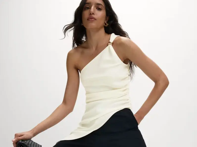 Woman wearing a cream asymmetric top and black trousers