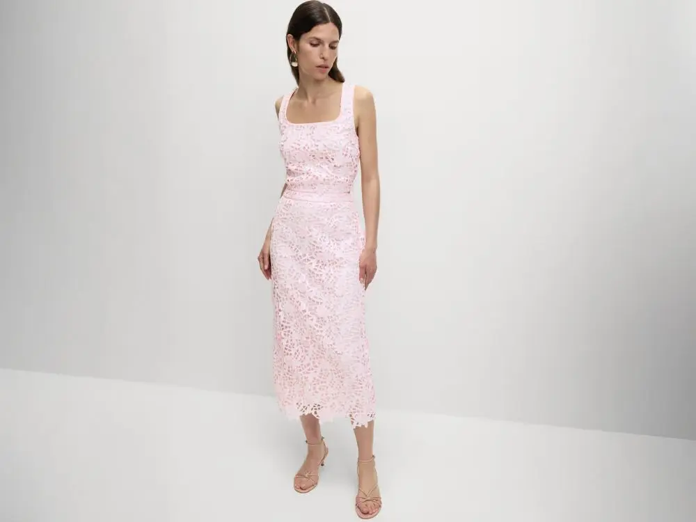 A woman wears a powder pink top and matching pencil skirt in powder pink