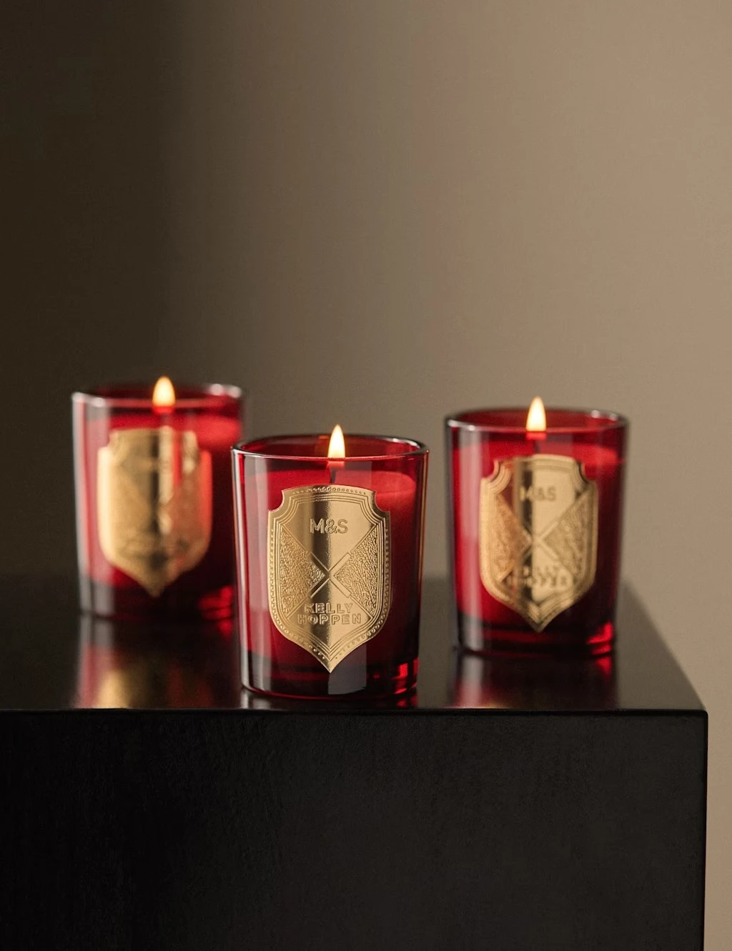 Group of three red Christmas candles with a gold crest.