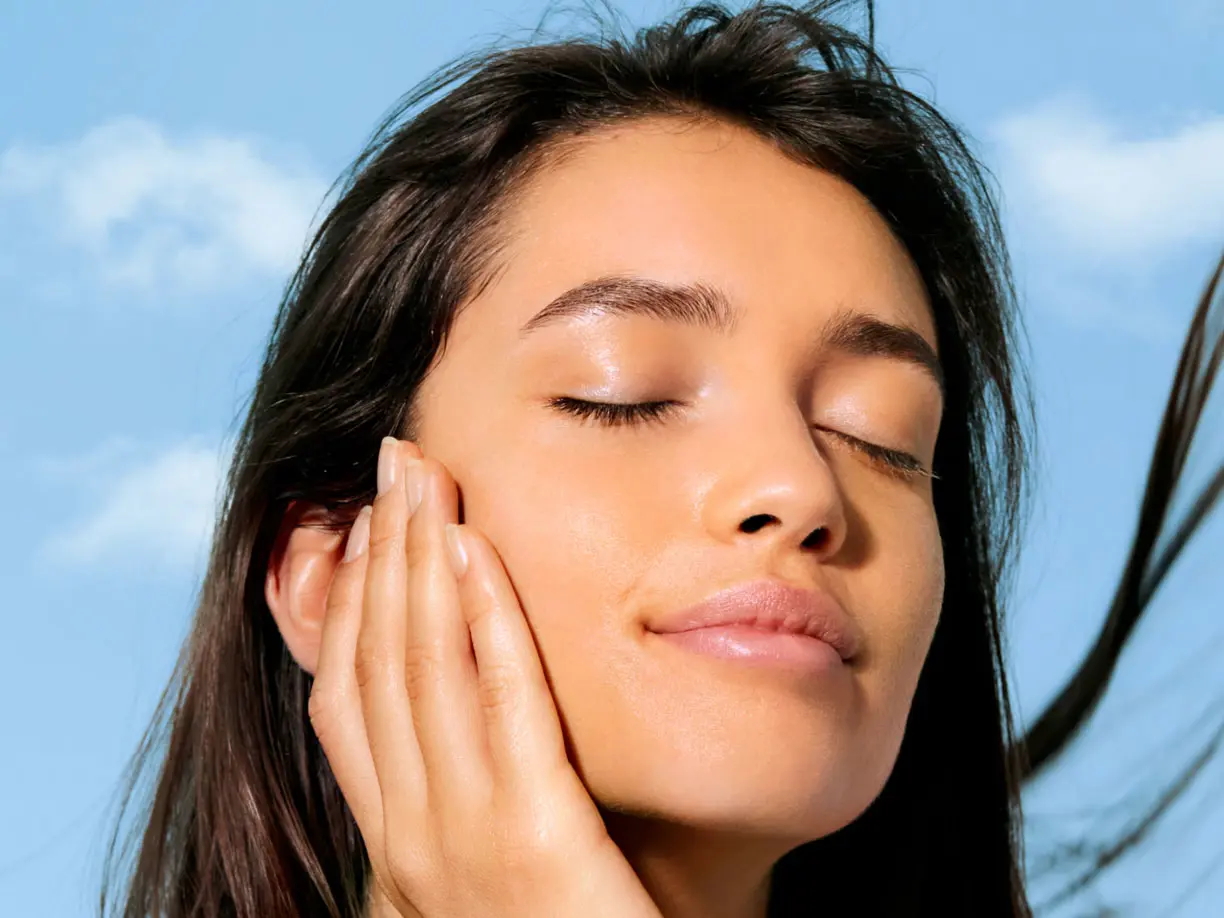 Woman with dark hair touching her face 