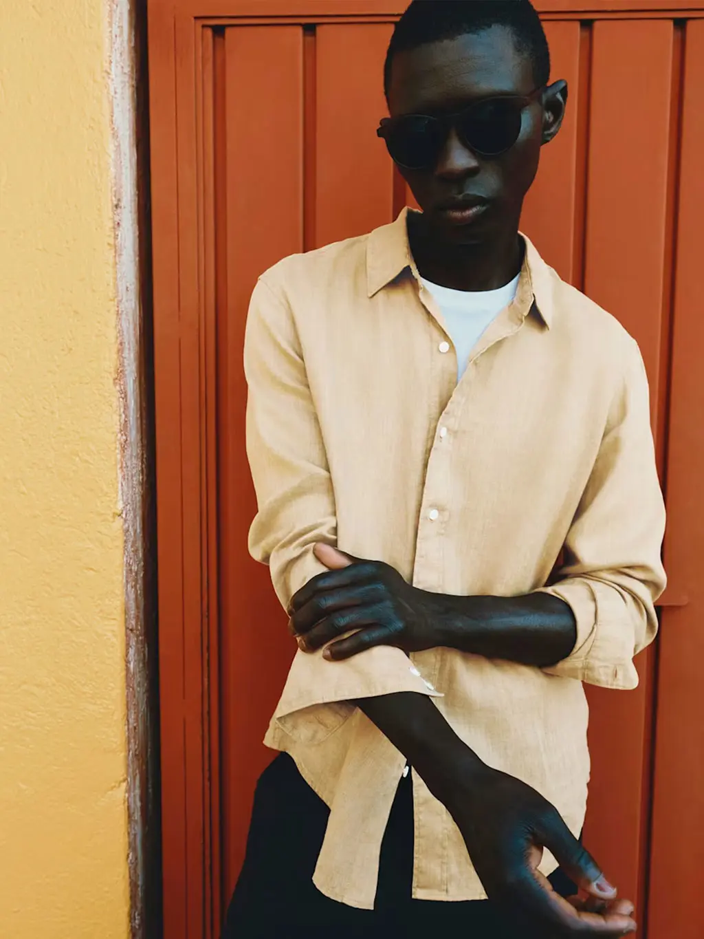 Man wearing a yellow linen shirt with a white T-shirt and black shorts