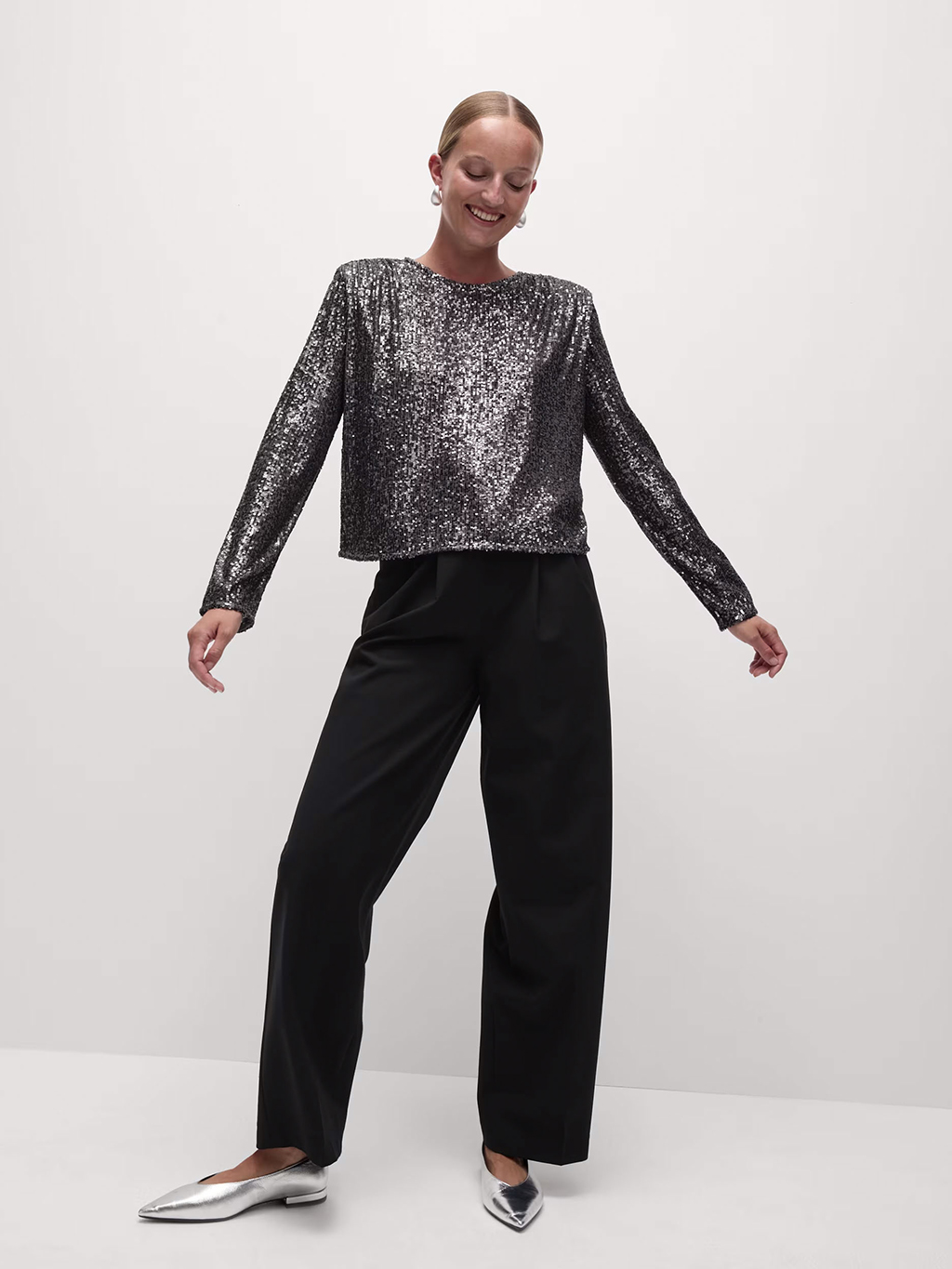 Woman wearing sequinned top and black trousers