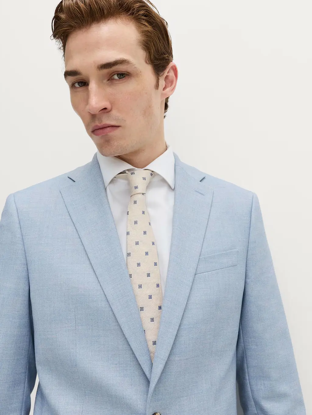 Man wearing a blue suit with a white shirt and patterned silk tie