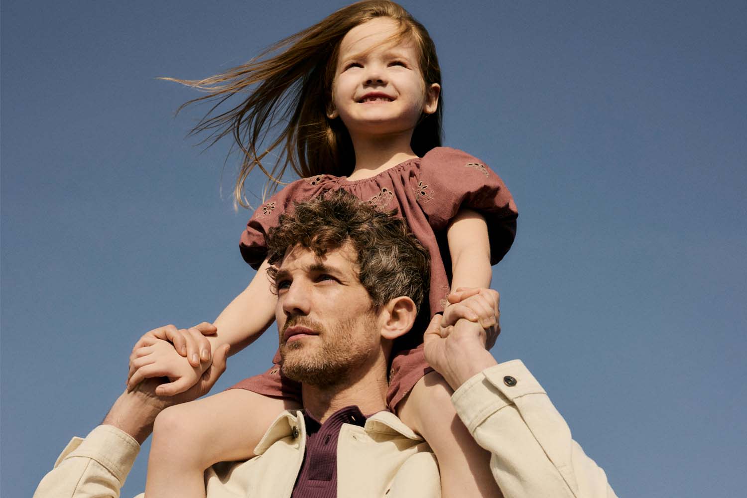 A picture of a dad with his daughter on his shoulders. 