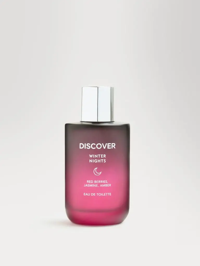 A product shot of a red Winter Nights by M&S perfume bottle against a pile background