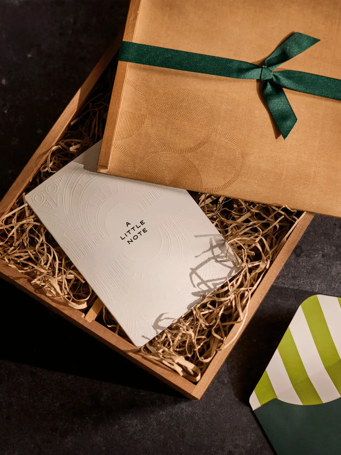 Gif of a bouquet of pink flowers, a gift box of chocolates, a candle and alcohol bottles, and a box with a green bow and white note paper