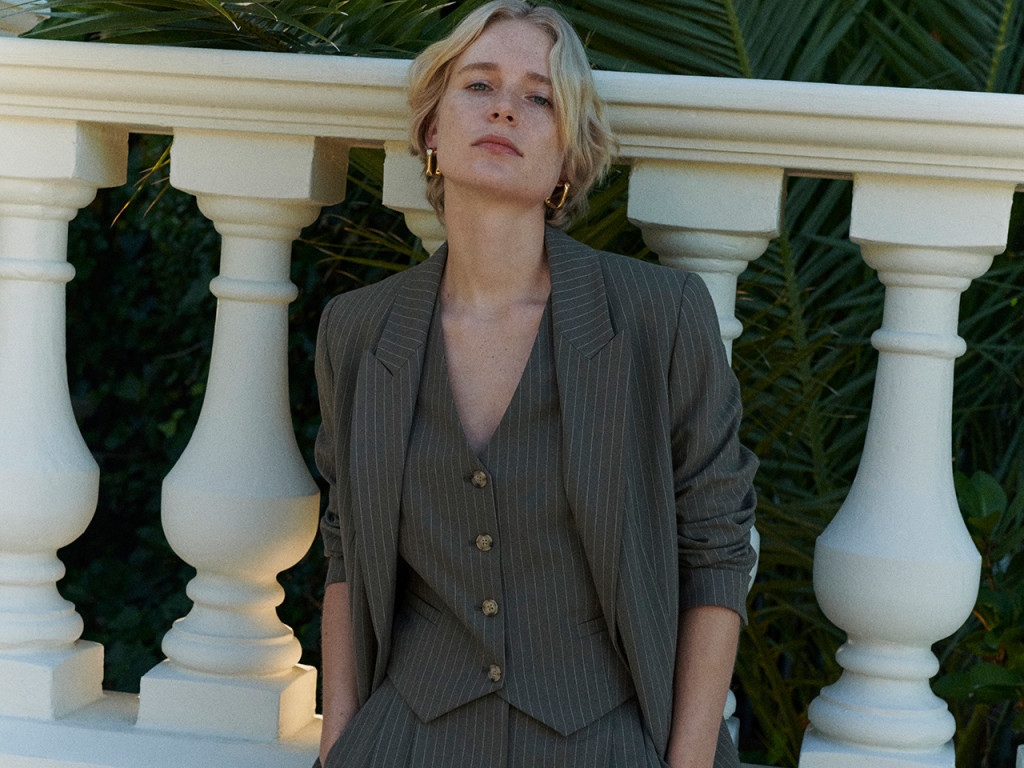 Woman wearing brown three piece suit. Shop suits