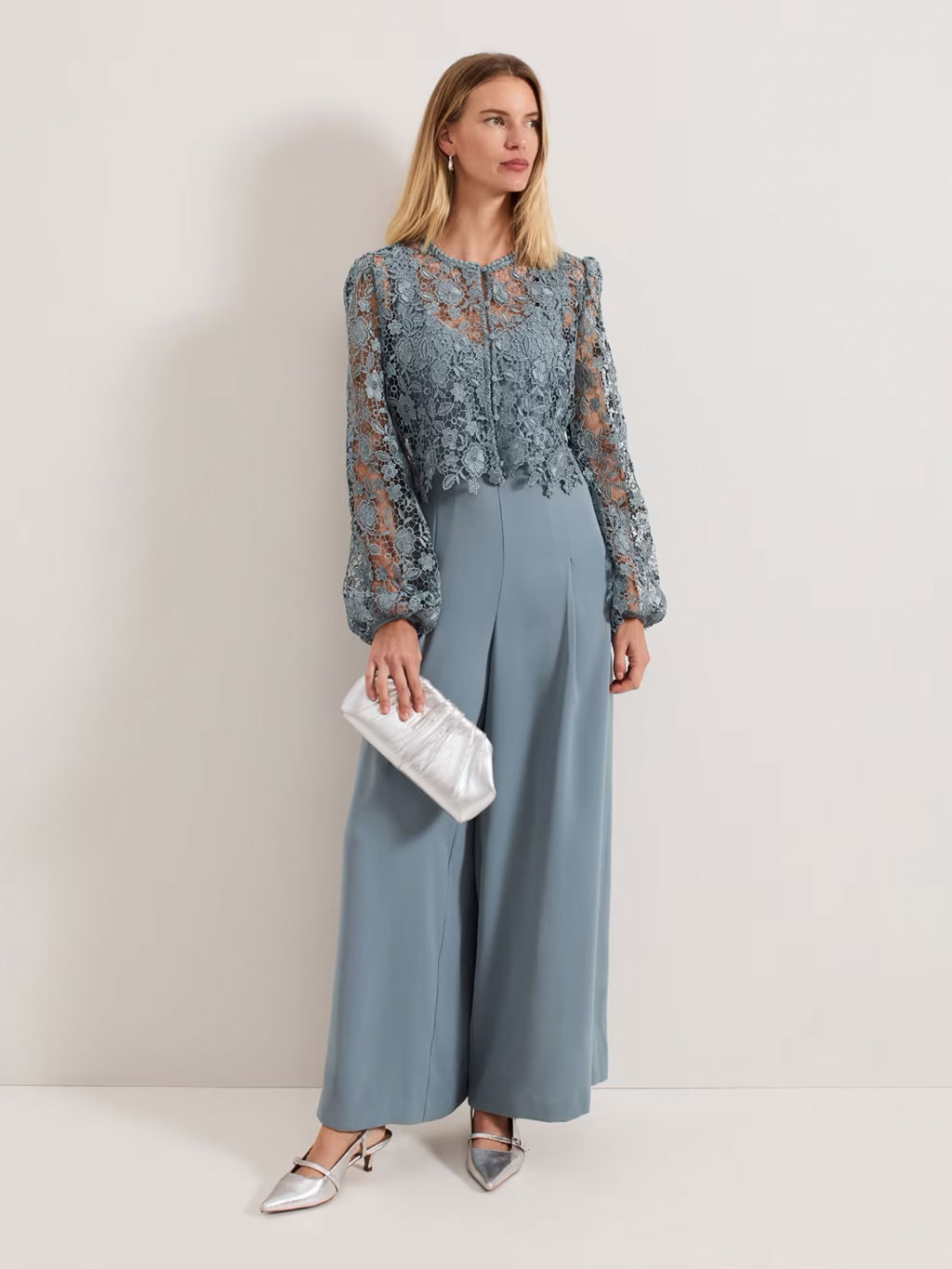 Woman wearing a blue lace and chiffon jumpsuit from Phase Eight at M&S
