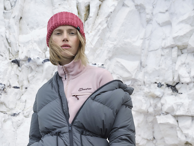 Woman wearing pink beanie hat, pink fleece and grey padded jacket 