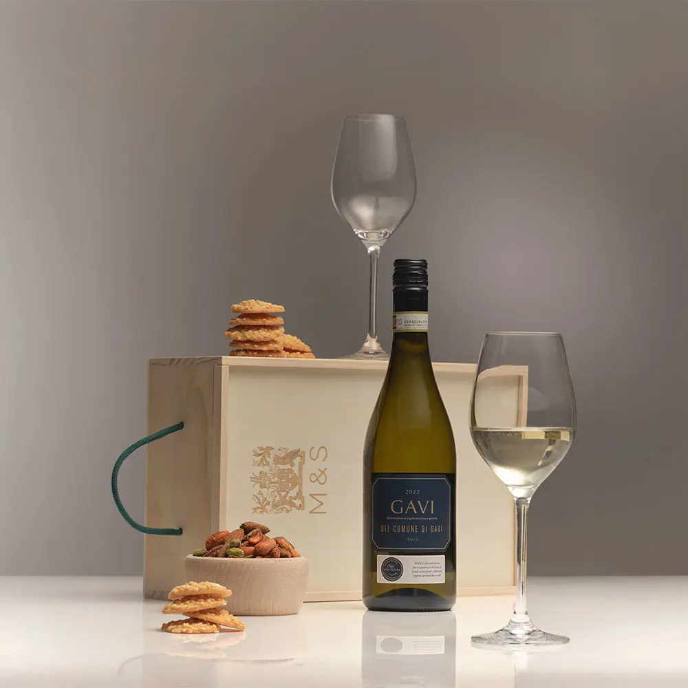 The contents of a hamper, including wine displayed in wine glasses alongside crackers