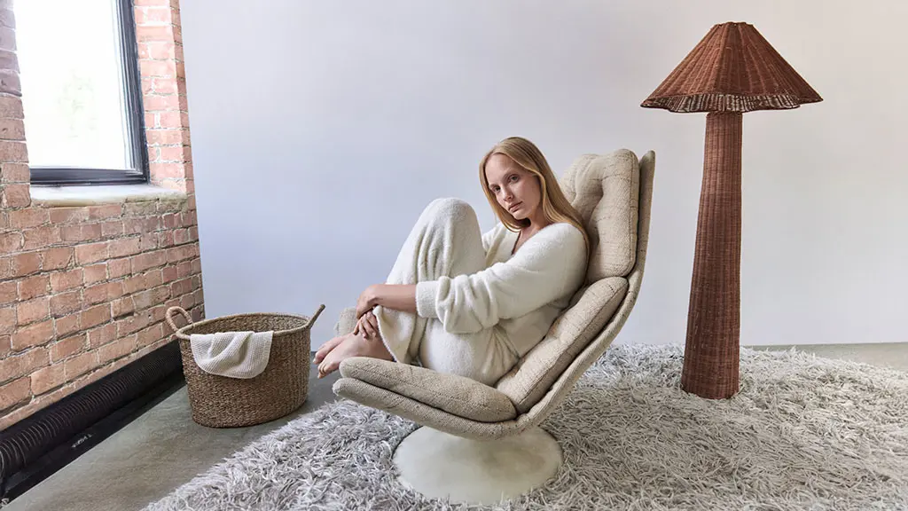 Woman wearing cream loungewear and sitting in a chair