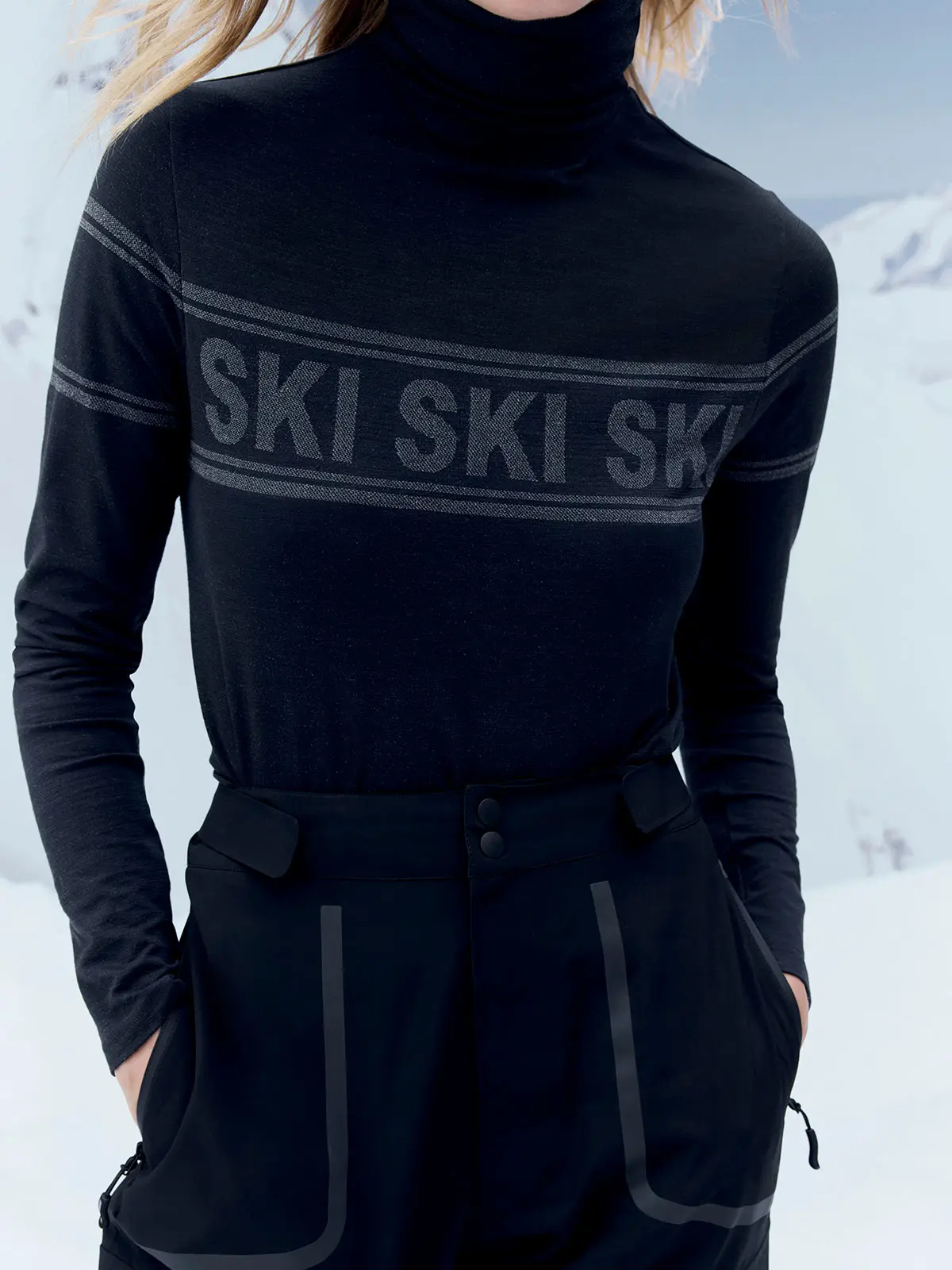 Woman wearing black jumper with slogan detail and black ski trousers 