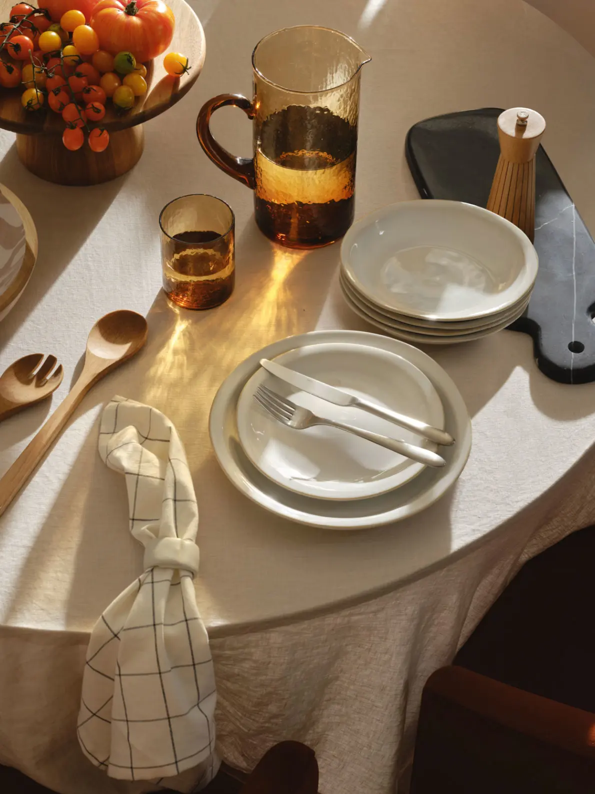Image of a table with plates, glassware, utensils and a bowl of fruit